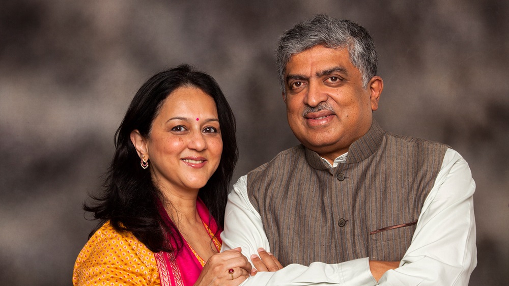 Philanthropists Rohini Nilekani (left) and Nandan Nilekani (right) smile. Rohini holds Nandan’s left arm in warm embrace.