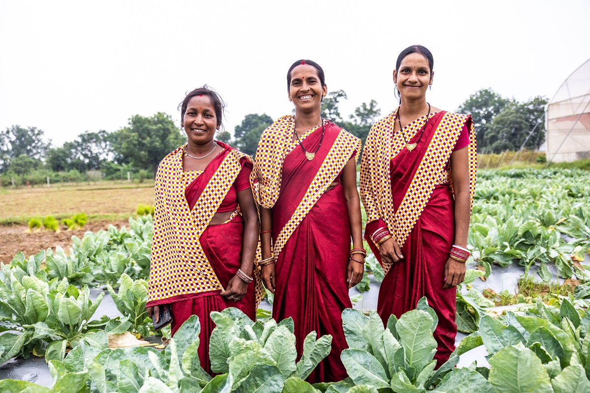 Three women in a field smiling.